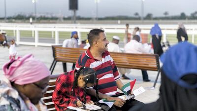A father and his daughter hold the UAE flag at Meydan. Reem Mohammed / The National