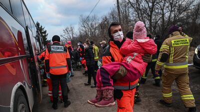 A polish paramedic carries a Ukrainian child to be put in a train carriage renovated for medical transport on March 10 in Medyka, Poland. About 20 children and their families were taken by bus to Medyka. Getty