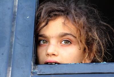 An evacuated Syrian girl looks out of a broken bus window as it passes the Al Eis crossing south of Aleppo during the evacuation of two pro-regime towns on July 19, 2018. AFP