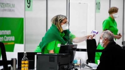 Medical staff use an infrared thermometer to measure the temperature on the forehead of an elderly man at a vaccination centre in Ludwigsburg, southern Germany. AFP