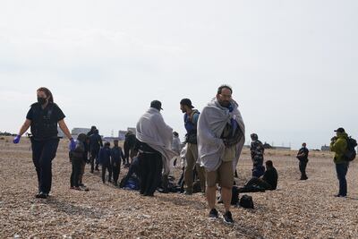 Immigration enforcement officers and members of the RNLI assist a group of migrants after they were brought to Dungeness beach in Kent on Monday. Photo: PA