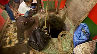 Mr Umar filling his mashaks with water from the well at the shrine in Delhi