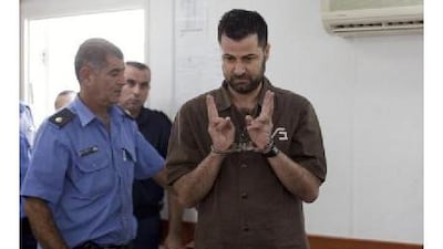 Abdullah Abu Rahme, 39, makes V-signs inside the courtroom at Ofer military jail near Ramallah yesterday during his sentencing. Mr Rahme's group of protesters opposed Israel's separation barrier.