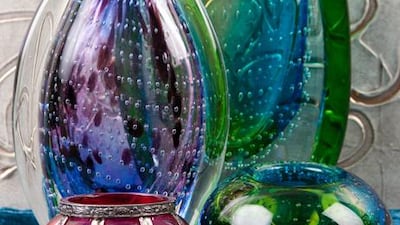 Large green and blue glass vase, Dh220 at Debenhams. Green and blue tealight holder, Dh80 at Debenhams. Red and gold tealight holder, Dh49 at ID Design. Purple and blue glass vase, Dh115 at Debenhams. Gold canvas (background), Dh2,199 at ID Design.