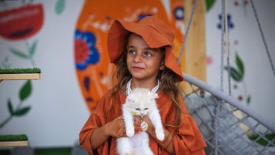 A girl plays with a cat at Meow Cafe. AFP