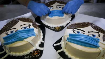 A Palestinian baker finishes a cake, that portrays a woman wearing a facemask, at his shop in Khan Yunis in the southern Gaza Strip. AFP