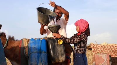 A man helps a girl to fill jerry cans with water from a cistern at a make-shift camp for displaced Yemenis, in the northern Hajjah province on April 29, 2020, amid a severe shortage of water. Essa Ahmed/ AFP