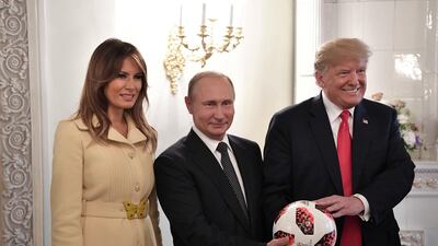 US President Donald Trump and First lady Melania Trump flank Vladimir Putin as the Russian president gifts a football in Helsinki, Finland. Reuters