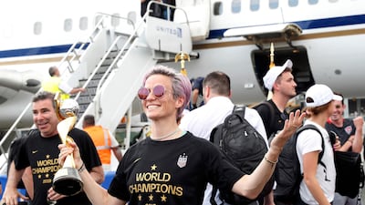 Megan Rapinoe holds the women's World Cup trophy after arriving with her United States teammates at Newark Liberty International Airport on Monday. Kathy Willens / AP Photo