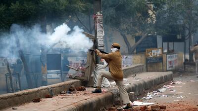 A policeman fires a teargas shell during a protest against a new citizenship law at the Seelampur area of New Delhi, India. AP