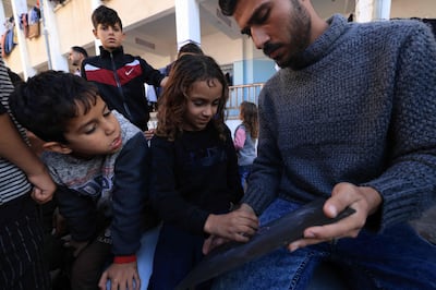 Tarek Al Annabi teaches displaced children sheltering at the Taha Hussein school in Rafah in the southern Gaza Strip on Wednesday. AFP