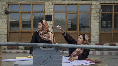 Election workers check voting machines as they prepare to distribute them to workers at a central collection point before heading to polling stations.
