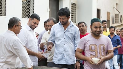 Volunteers help hand out kanji outside Lootah Mosque.