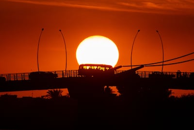 A bus crosses the Shatt al-Arab Bridge at sunset in the southern Iraqi port city of Basra, near the border with Kuwait, on December 3, 2021. AFP