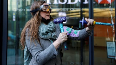 An activist from Extinction Rebellion smashes a window at HSBC headquarters during a protest in Canary Wharf, London. Reuters