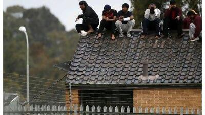Asylum seekers threaten to jump off the roof of the Villawood immigration detention centre in Sydney during a protest in September.