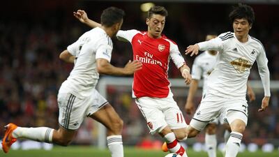 Mesit Ozil, centre, and his Arsenal teammates are looking to bounce back from Monday night's defeat to Swansea City. Alistair Grant / AP Photo