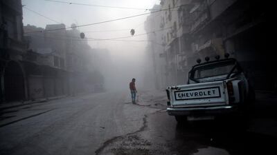 A Syrian man walks amid a street covered with dust following a reported air raid by government forces in the old city of Aleppo. Ahmed Deeb / AFP