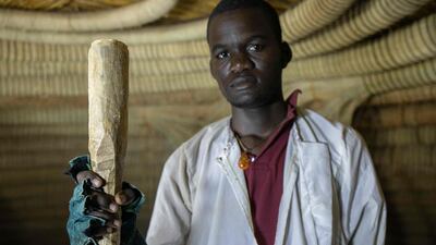 An artisan with a handmade club used to hit thatching into shape.