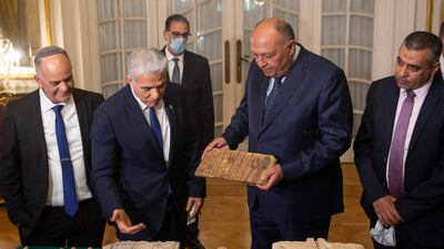 Israel Antiquities Authority Director Eli Escozido, left, looks on as Mr Lapid, centre left, presents Mr Shoukry with the stolen Egyptian artefacts. AFP
