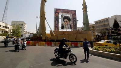 Iranians walk past Sejjil (L) and Qadr-H medium range ballistic missiles displayed next to a portrait of Iranian Supreme Leader Ayatollah Ali Khamenei on the occasion of the annual defence week which marks the anniversary of the 1980s Iran-Iraq war, on September 25, 2017. Atta Kenare / AFP PHOTO