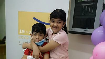 Sidrathul Munthaha, 9, from Bangladesh, with her younger brother after they received their first shot of the Sinopharm Covid-19 vaccine.
