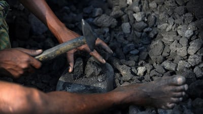 A miner breaks up pieces of coal at a depot in Siliguri. A report in 2012 alleged that India lost out on more than US$33 billion because coal mining permits were awarded to companies without an auction process. Diptendu Dutta / AFP