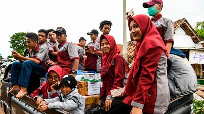 Residents ride in a truck near an area of collapsed houses in Rajabasa. AFP