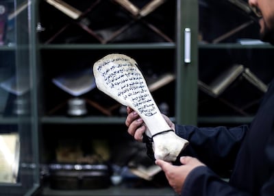 Salem Al Jadidi holds a bone with Arabic text that belonged to his uncle. Reem Mohammed/The National
