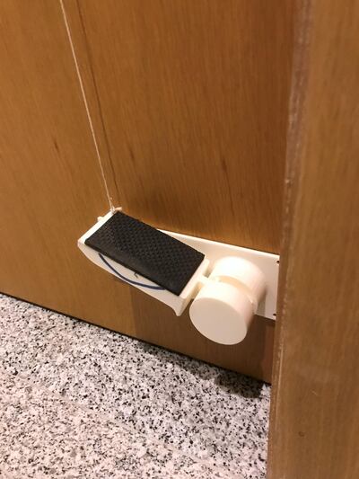 The pivot and lever system consists of only two parts: a rectangular white base can that can be stuck to the base of a door and a cord attached to the door handle.