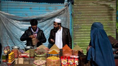 An Afghan street vendor, left, sells spices to a customer in Kabul. Afghanistan’s economy is recovering from decades of conflict but despite the significant improvement in the last decade it is extremely poor, and highly dependent on foreign aid. Nicolas Asfouri / AFP