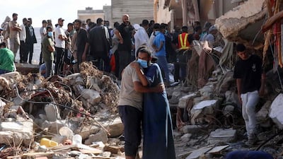 Two men comfort each other as people check the damage caused by a flash floods after Storm Daniel hit Libya's eastern city of Derna. AFP