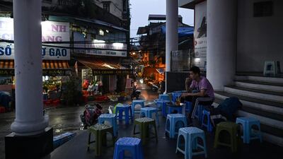 This picture taken on March 23, 2020 shows a man sitting alone at a street-cafe, amid concerns over the spread of the COVID-19 novel coronavirus, in Hanoi. / AFP / Manan VATSYAYANA