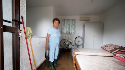 A woman attempts to clear flood water from her home in the village of Achladi, in northern Evia. AP Photo