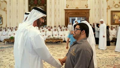 Sheikh Mohamed shakes hands with a member of Zayed Higher Organisation for People of Determination.