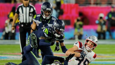New England Patriots' Hunter Henry, right, is tackled by Seattle Seahawks' Riq Woolen. Reuters