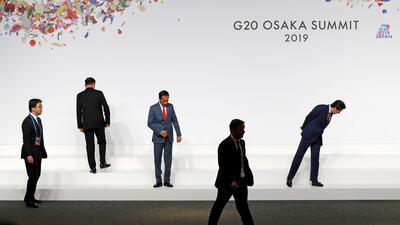 Japanese Prime Minister Shinzo Abe (R) and Indonesian President Joko Widodo (C) check their positions as they prepare for family photo session at the G20 leaders summit in Osaka, Japan. Reuters