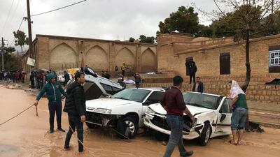 People stand near destroyed cars after a flood hit the city of Shiraz. EPA