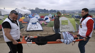 Medical volunteers carry a woman on stretcher after she collapsed at a refugee camp on the Greek-Macedonian border. Marko Djurica / Reuters