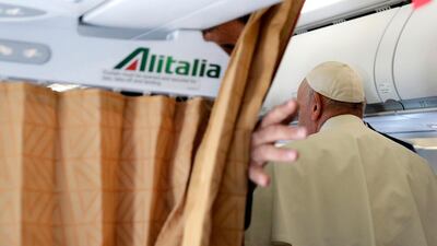 Pope Francis returns to his seat after meeting with reporters aboard his plane. AFP