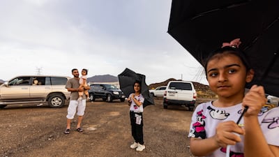 A family stops to enjoy the rain along the Wadi Shawqa road in Ras Al Khaimah. Antonie Robertson/The National
