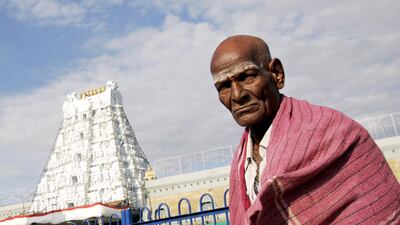 A devotee stands in front of the Tirupati temple complex in India's southern state of Andhra Pradesh after cutting off his hair as an offering. Dibyangshu Sarkar / AFP