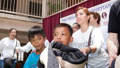 Etihad Airways Employee, Luzelle Boado, right, hands out donated blankets to students of the PCF School. Mike Young for the National