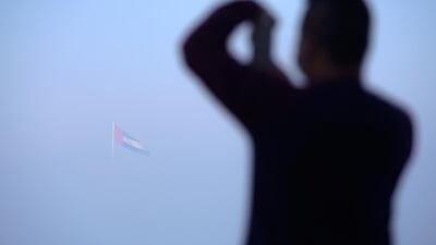 A Corniche stroller takes a photo of the UAE flag as it emerges from the fog. Victor Besa / The National