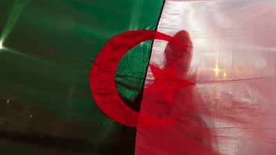 A man is silhouetted through an Algerian flag as he celebrates with others after Algerian President Abdelaziz Bouteflika announced that he is delaying the April 18 election and won't seek another term, in Algiers, Algeria. Bouteflika bowed to unprecedented public protests Monday and promised not to seek a fifth term after 20 years in power. AP