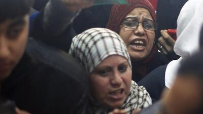 Two Palestinian women hoping to cross into Egypt shout toward border officials, as they wait with other Palestinians to register their names at the Rafah crossing between Egypt and the southern Gaza Strip.