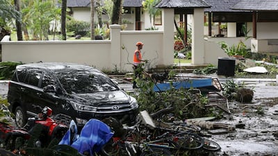 A police officer carries his K9 unit search dog as they continue to search for victims at Tanjung Lesung beach. AP