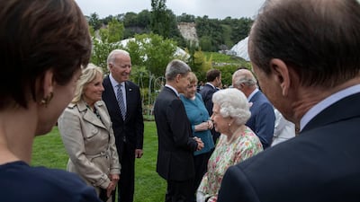 Britain's Queen Elizabeth II, in a floral dress, speaks to US President Joe Biden, centre left and first lady Jill Biden, who wore a Gabriela Hearst trench coat for the occasion. Reuters