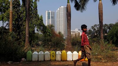 A boy walks past plastic containers filled with drinking water at a tribal settlement in Mumbai, India, on March 29, 2018. Francis Mascarenhas / Reuters