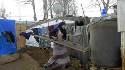 Syrian refugees like this woman carrying wood outside her makeshift shelter will soon be benefiting from more UAE aid. Wael Hamzeh / EPA